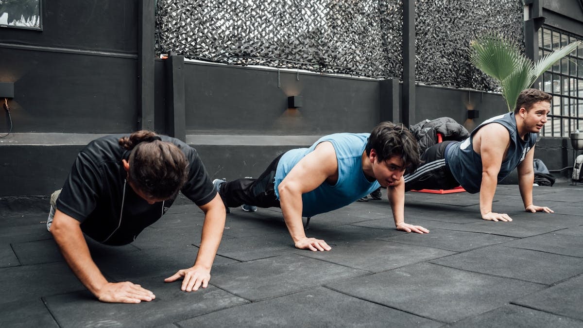 Men performing push-ups during a group workout session in Mexico City gym.